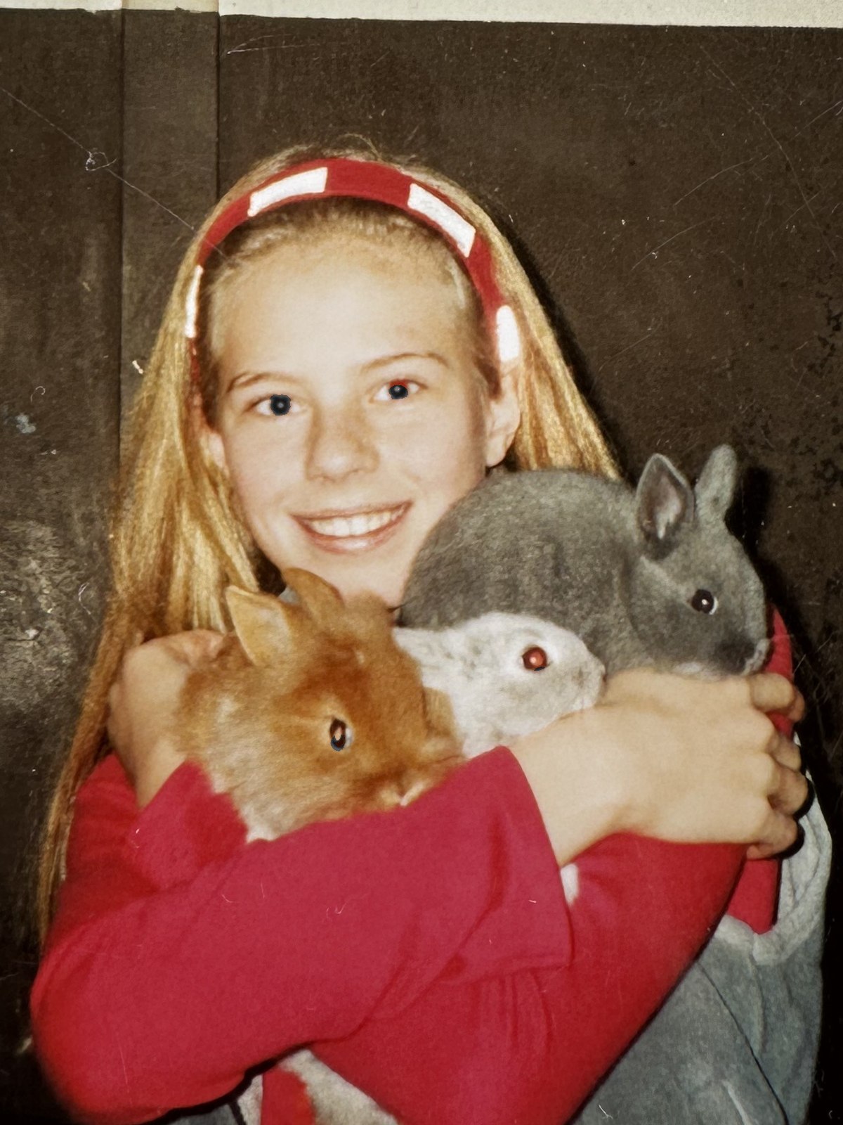 A young Zilla van den Born holding three pet rabbits