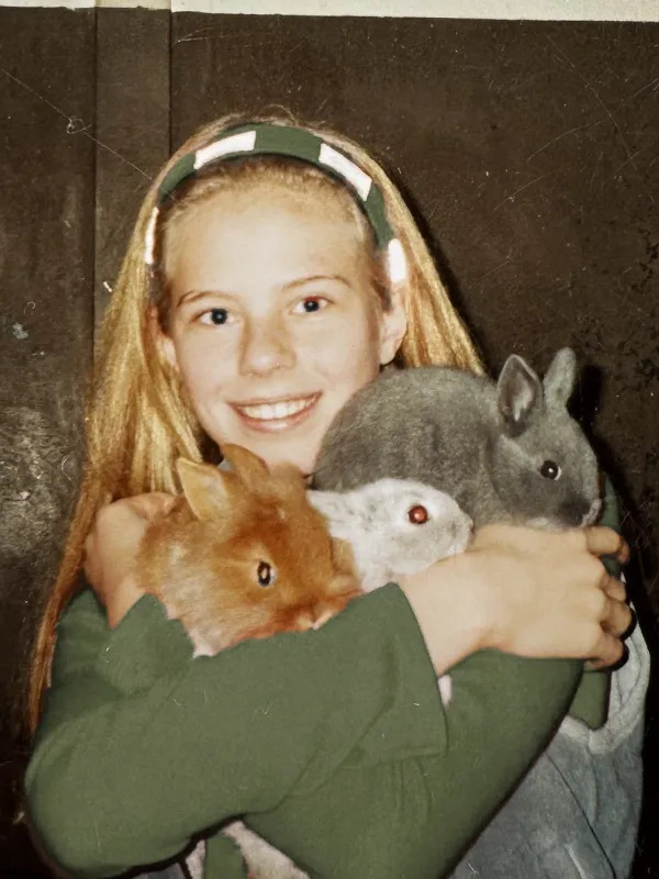 A young Zilla van den Born holding three pet rabbits